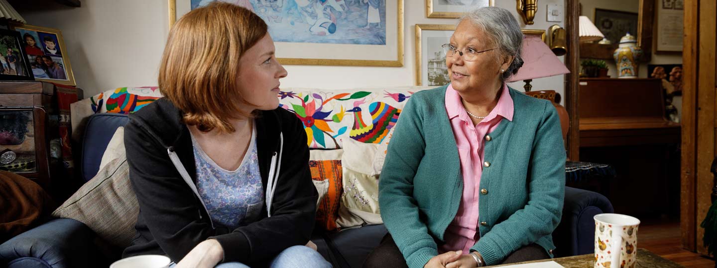 Graciela and Fiona sat in a living room talking with a cup of tea.