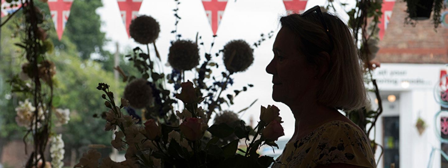 Silhouette of a lady in a window with some flowers.