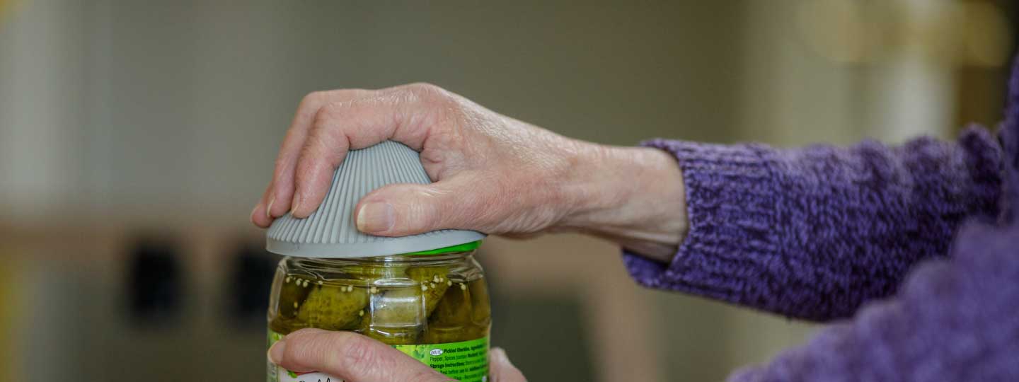 A lady opening a jar with a gadget to help her.