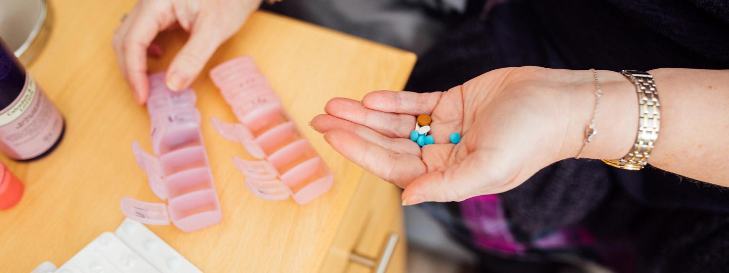 Debs holding a pile of tablets in her hand, signifying how many she needs to take each day to be pain free.