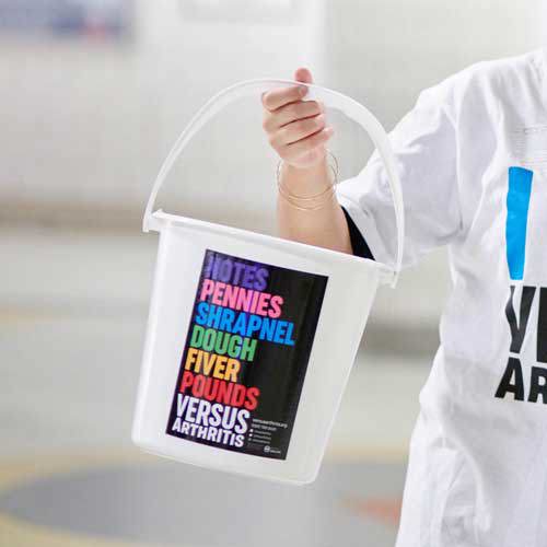 Someone holding a bucket with the Versus Arthritis logo on.
