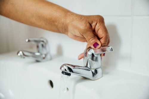Woman turning lever taps