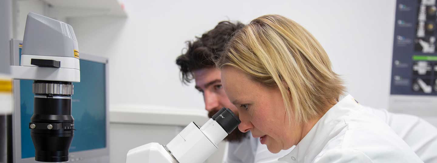 Two scientists looking through a microscope.