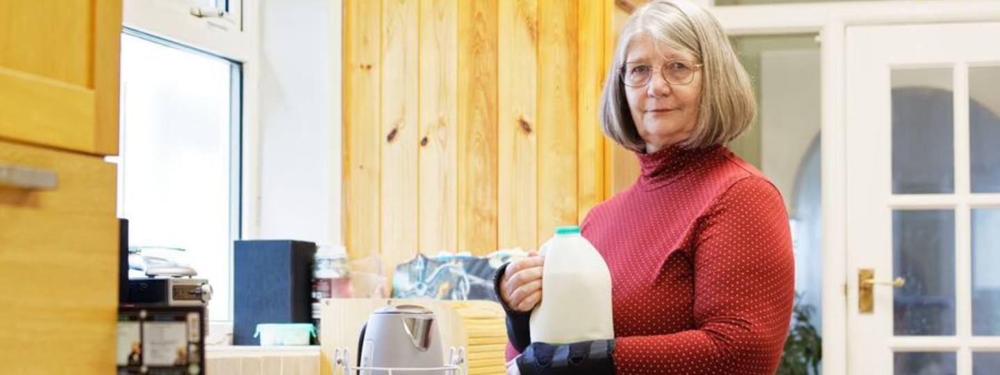 Yvonne carrying a pint of milk close to her body practicing joint protection