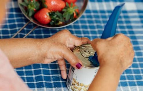 Woman using can opener aid