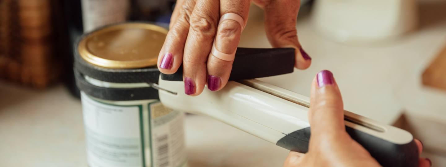 Woman using a tin opener aid