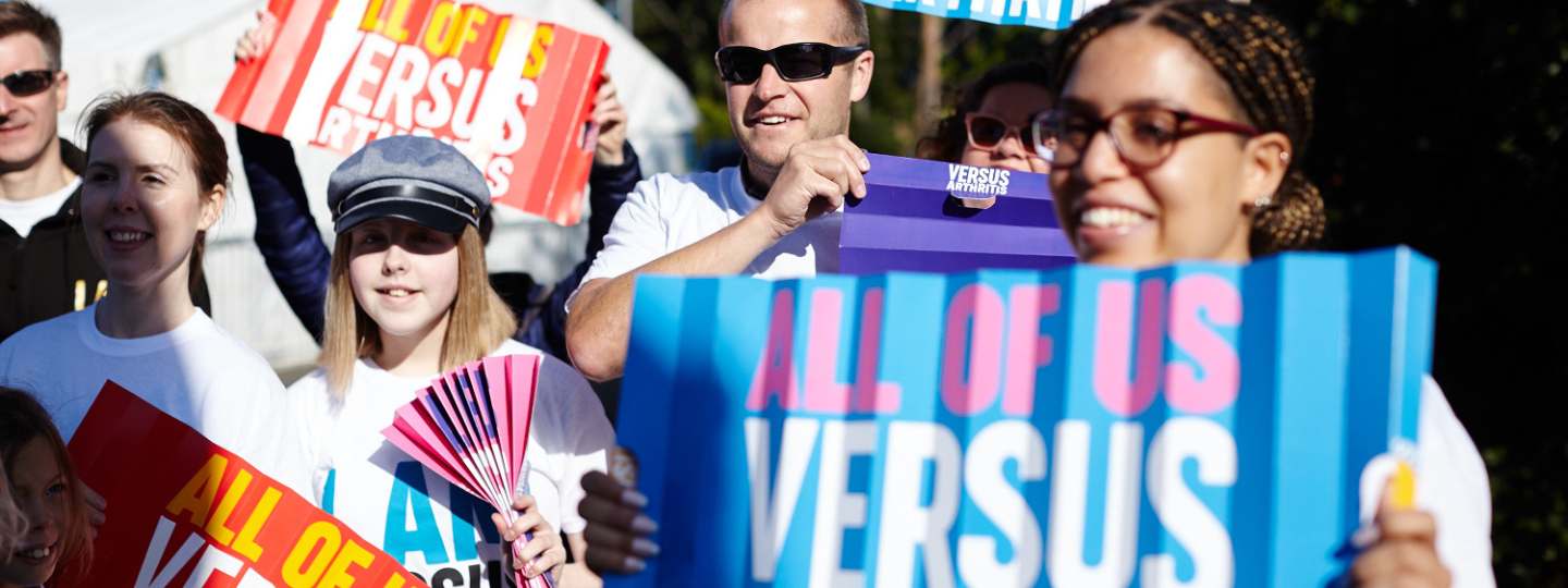 Crowd holding Versus Arthritis signs at marathon