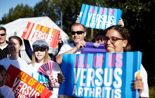 Crowd cheering and holding signs to encourage Versus Arthritis walkers and runners