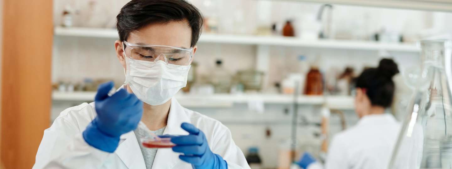 Man wearing white lab coat taking a scientific sample in a laboratory 