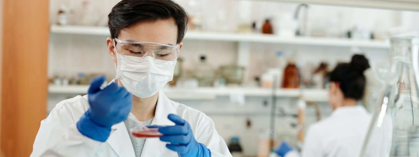 Man wearing white lab coat taking a scientific sample in a laboratory