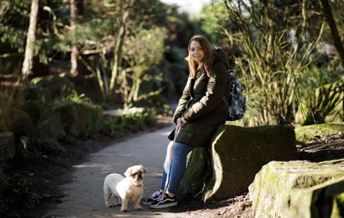 Poppy sitting on a stone wall with her dog in nature