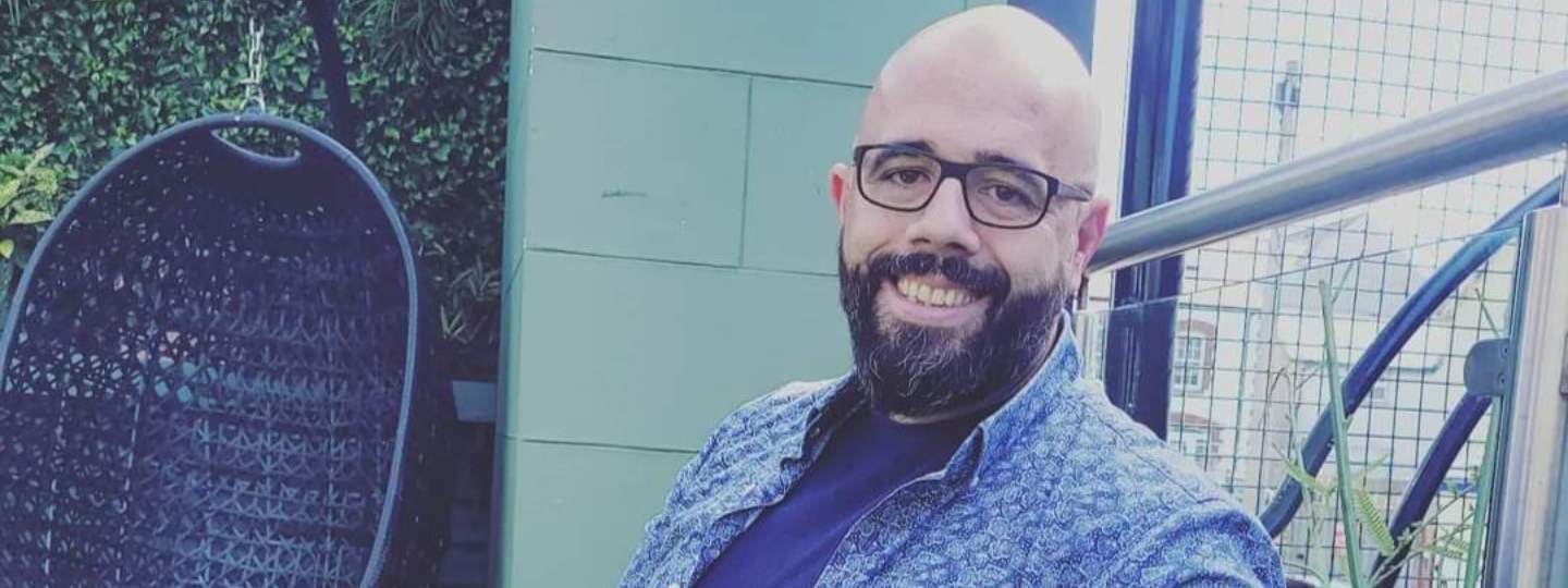 Smiling man with beard wearing glasses sitting in garden