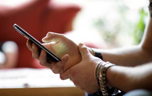 Man wearing silver bracelet using phone