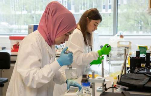 Two female researchers using pipettes