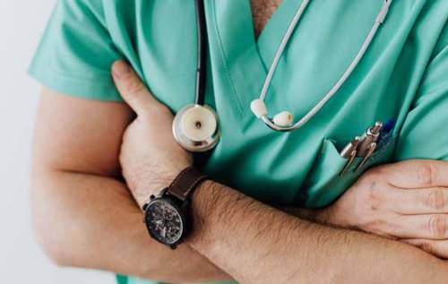 Doctor wearing green scrubs with hands crossed