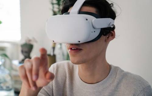 Young man using virtual reality (VR) headset and pointing to the air