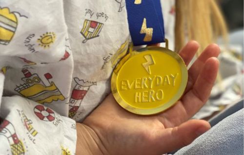 Mali holding a gold medal which reads 'everyday hero'