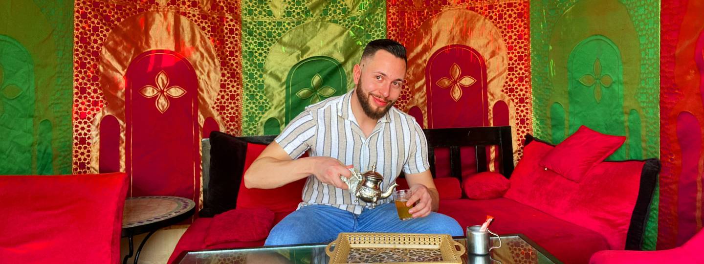 Smiling James wearing striped shirt pouring tea in Morocco