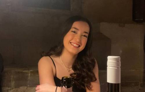 Smiling photo of Georgia in front of wine bottle