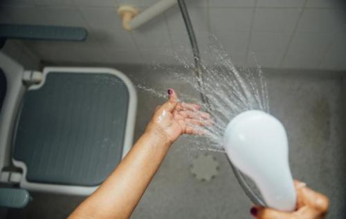 Woman using shower head beside seat