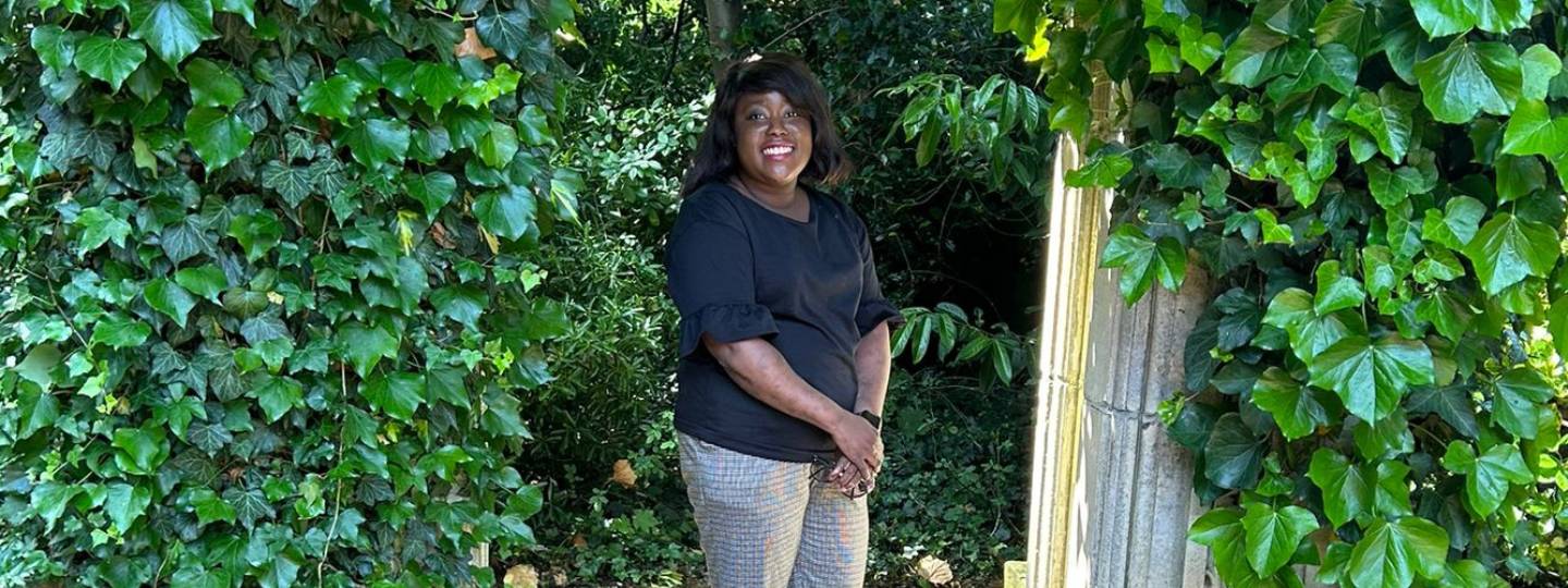 Smiling Melissa standing in lush green garden covered in ivy