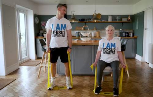 Leon standing and his mum Janet sitting holding a resistance band under their feet