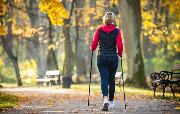 A Woman Walking In The Woods With Poles