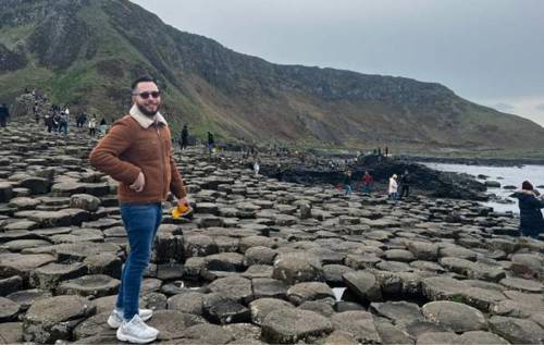 Smiling James wearing sunglasses and furlined coat at the Giant's Causeway in Northern Ireland