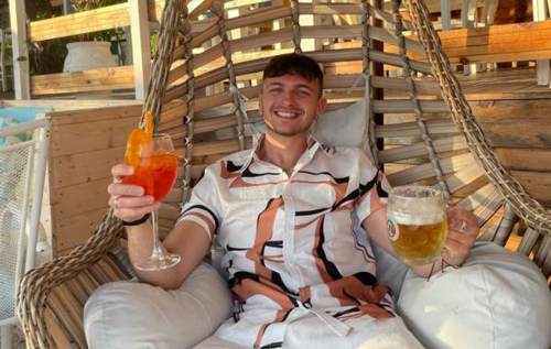 Isaac holding a cocktail and beer