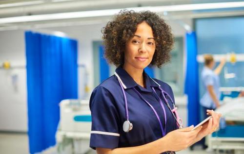 Smiling nurse with curly hair standing in a hospital