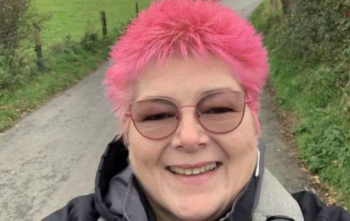 Smiling Louise who has pink hair and cat-eyed sunglasses on a walk