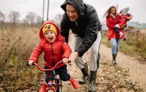 Father pushing son on tricycle