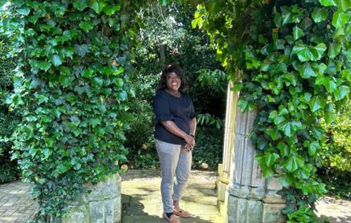Smiling Melissa wearing black top standing in lush green garden