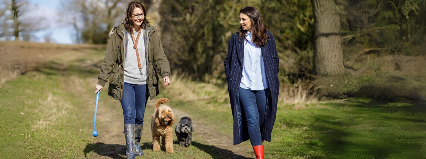 Two woman walking dogs in countryside