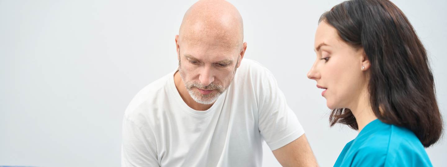 Nurse listening to male patient wearing white t-shirt