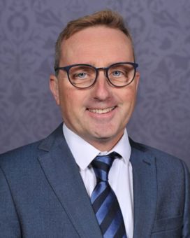 Professor Christian Mallen smiling wearing suit and glasses