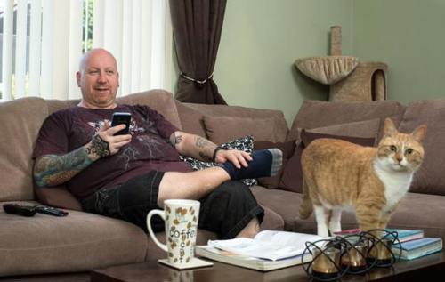 Neil sitting on living room sofa beside a ginger cat